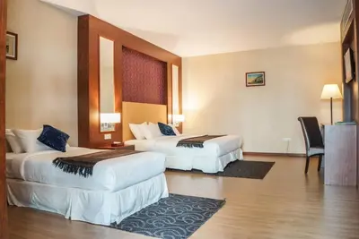 a hotel room with two beds and a chair at Hotel Pen Mutiara in Kampong Batu Maung