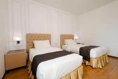 two beds in a room with white walls and wood floors at Hotel Pen Mutiara in Kampong Batu Maung