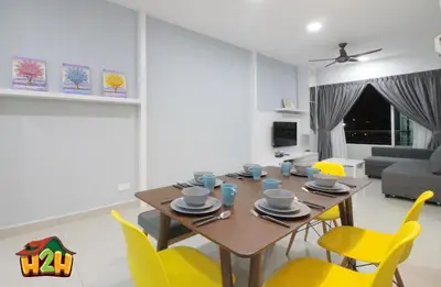 a dining room and living room with a table and yellow chairs at H2H - TT Court Majestic Ipoh in Ipoh