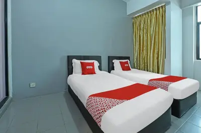 two beds with red pillows in a room at Hotel O Purple Town in Sekincan