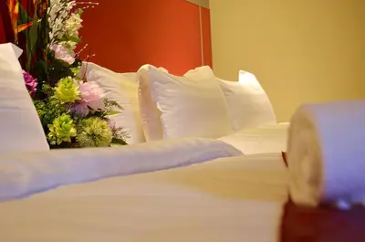 a bed with white pillows and flowers on it at Hotel Eastana Ipoh in Ipoh