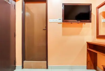 a room with a television on a wall with a door at My Town Hotel in Ipoh