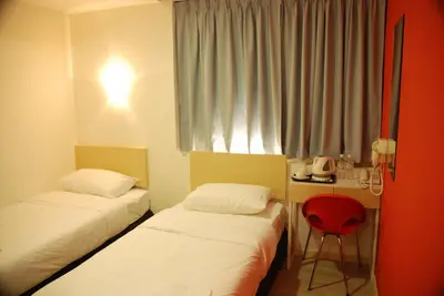a room with two beds and a desk with a red chair at Old Penang Hotel - Penang Times Square in George Town