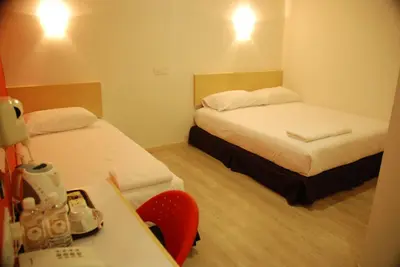 a hotel room with two beds and a desk with a table at Old Penang Hotel - Penang Times Square in George Town