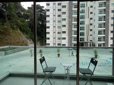 a balcony with two chairs and a table and a pool at ICOLOR HOME & STAY CH 8 in Tanah Rata