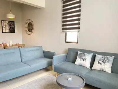a living room with two blue couches and a table at Arcadia Penang by Plush in George Town