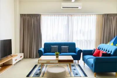 a living room with blue couches and a tv at By The Sea Beach Front Apartment in Batu Ferringhi