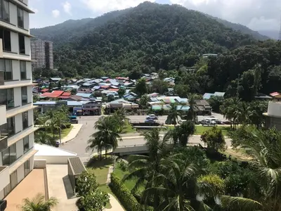 a view of a city with a mountain in the background at By The Sea Beach Front Apartment in Batu Ferringhi