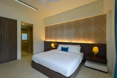 a bedroom with a large white bed and two lamps at By The Sea Beach Front Apartment in Batu Ferringhi