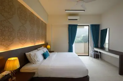 a hotel room with a bed and a window at By The Sea Beach Front Apartment in Batu Ferringhi
