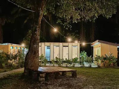 a wooden bench sitting under a tree next to a building at Outworld Basecamp in Gopeng