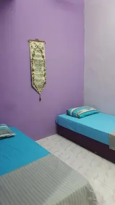 two twin beds in a room with purple walls at Cottage Muslim Homestay ByWawaSha in Tanjung Malim