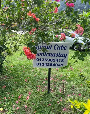 a sign in the middle of a yard with flowers at Yellow Cube at Lumut Cube Homestay Kontena in Lumut