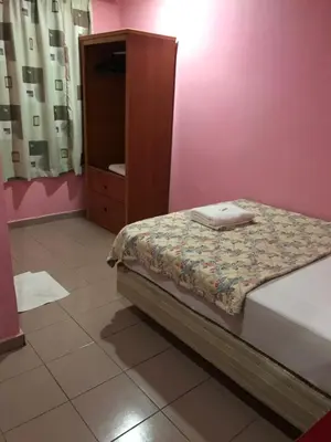 a small bedroom with a bed and a cabinet at Hotel Cahaya in Tanjung Malim