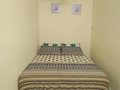 a bed in a room with two pictures on the wall at Homestay / Roomstay Muslim Budget Tanjung Malim in Tanjung Malim