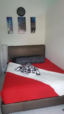 a bed with a red and white blanket and a clock at Homestay / Roomstay Muslim Budget Tanjung Malim in Tanjung Malim