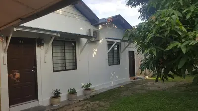 a white house with a brown door and some plants at Homestay / Roomstay Muslim Budget Tanjung Malim in Tanjung Malim