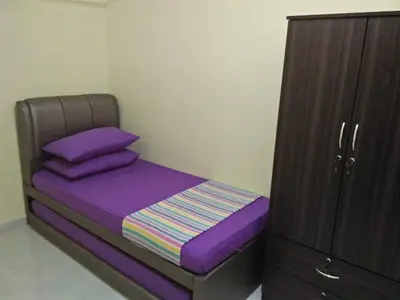 a bed with purple sheets next to a wooden cabinet at Homestay / Roomstay Muslim Budget Tanjung Malim in Tanjung Malim