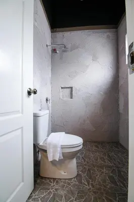 a bathroom with a toilet and a white wall at Art Cottage Hotel in Ipoh