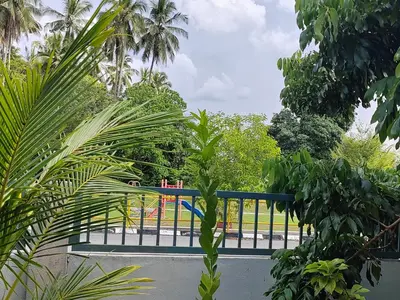 a fence with a playground in a park with palm trees at Teratak Delisha -musslim in Kampong Jemampar