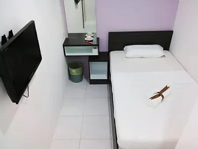 a small bedroom with a bed and a tv at Hotel Checkedinn in Ipoh