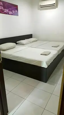 two beds in a room next to a wall at Hotel Checkedinn in Ipoh
