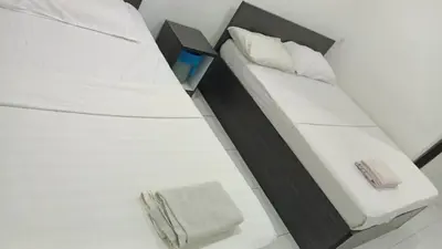 a bedroom with a white bed with white sheets at Hotel Checkedinn in Ipoh