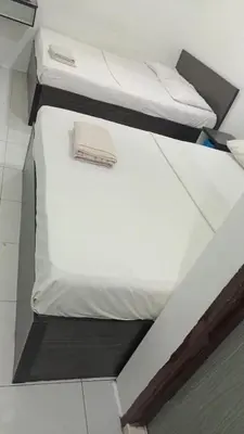 two beds in a room with white sheets at Hotel Checkedinn in Ipoh