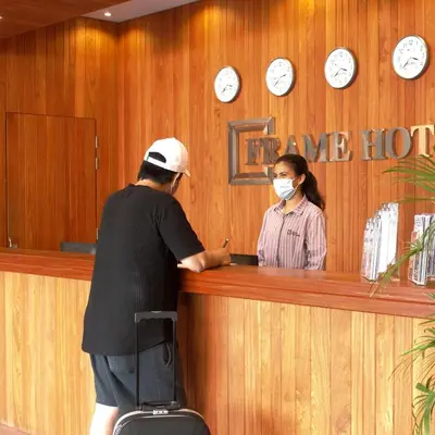 a man and a woman are standing at a counter at Frame Hotel in George Town