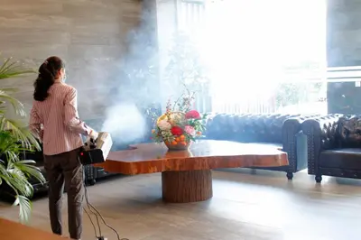 a woman standing next to a table with a vase of flowers at Frame Hotel in George Town