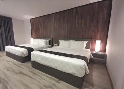 a hotel room with two beds and a wooden headboard at Frame Hotel in George Town
