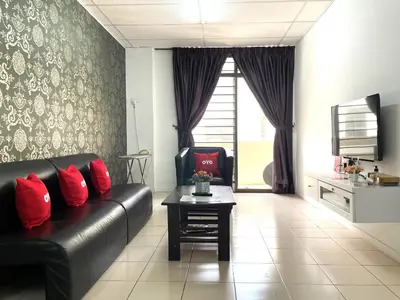 a living room with a black leather couch and red pillows at Hotel O Wg Guest House in George Town