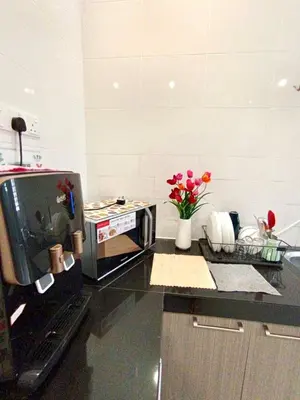 a kitchen with a microwave and flowers on a counter at TROPICAL LIVINGS MERU IPOH HOMESTAY by Grab A Stay in Ipoh