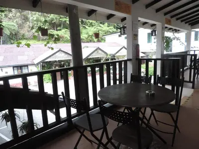 a table and chairs on a porch with a view of the street at Cameronian Inn in Cameron Highlands