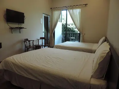 two beds in a room with a tv and a window at Cameronian Inn in Cameron Highlands