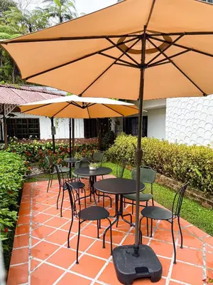 a group of tables and chairs under an umbrella at Cameronian Inn in Cameron Highlands