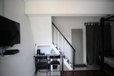 a room with a table and chairs and a staircase at Tiny Boutique Habitat in Tanah Rata