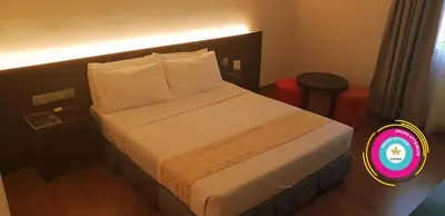 a hotel room with a bed with white sheets and pillows at Hotel Seri Malaysia Sungai Petani in Sungai Petani