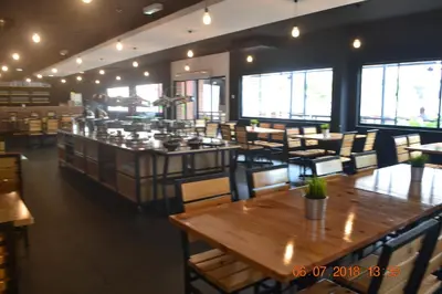 a restaurant with wooden tables and chairs and windows at Hotel Seri Malaysia Sungai Petani in Sungai Petani