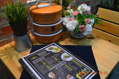 a table with a menu and flowers on it at Hotel Seri Malaysia Sungai Petani in Sungai Petani
