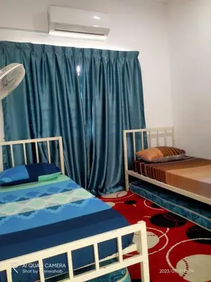 two beds in a room with green curtains at Sri Manik Guest House Tanjung Karang in Tanjung Karang
