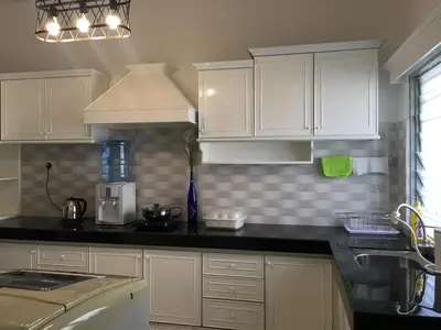 a kitchen with white cabinets and a black counter top at Ipoh Station 18 in Ipoh