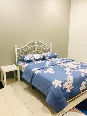 a bed with a blue blanket with flowers on it at Homestay Cahaya 2 Seri Iskandar in Seri Iskandar