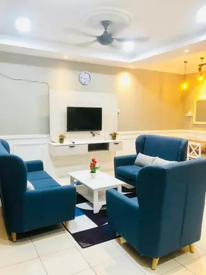 a living room with two blue chairs and a tv at Homestay Cahaya 2 Seri Iskandar in Seri Iskandar