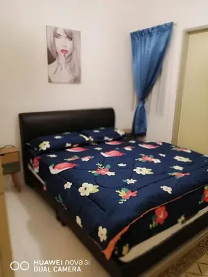 a bed with a blue comforter with flowers on it at alyaleesya homestay Teres in Brinchang