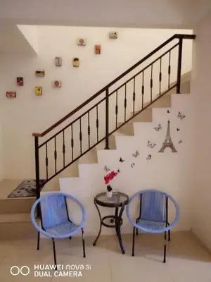 two blue chairs and a table under a staircase at alyaleesya homestay Teres in Brinchang