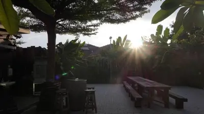 a sun shining through a fence with a picnic bench at Kinta Bali Villa in Ipoh