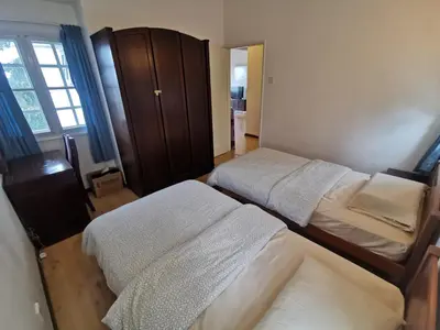 a bedroom with two beds and a wooden cabinet at Little England B8 in Bukit Fraser