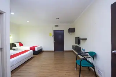 a room with two beds and a table and a chair at T P Hotel in Sitiawan