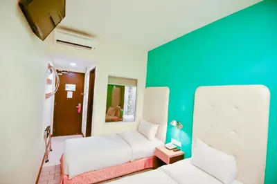 a bedroom with two beds and a green wall at Ritz Suites in Lumut